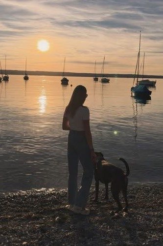 Eva und Buddy am Seeufer im Sonnenuntergang, im Hintergrund Segelboote